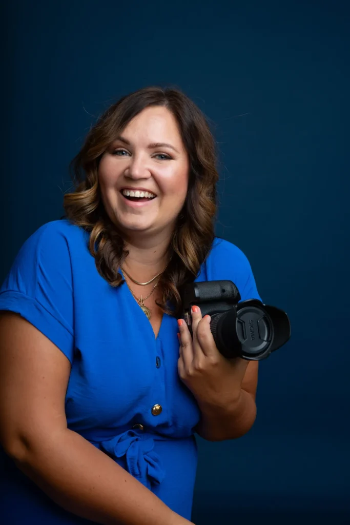 Fotografin Lisa Schmalzer lacht, Kamera in der Hand, blaues Kleid