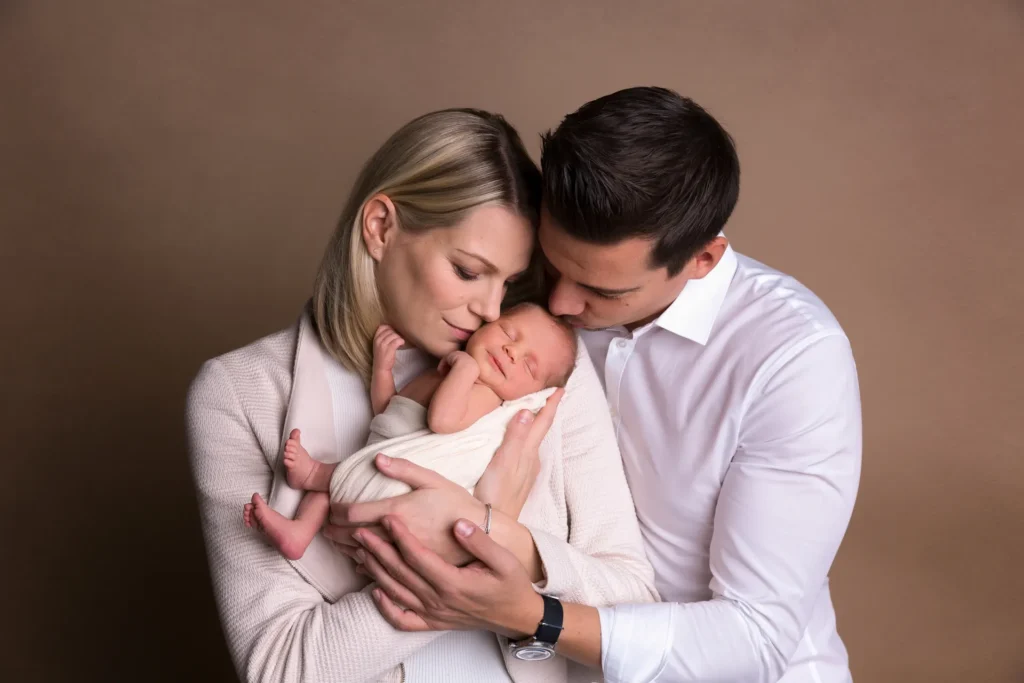 Eltern mit Baby vor beigem Grund