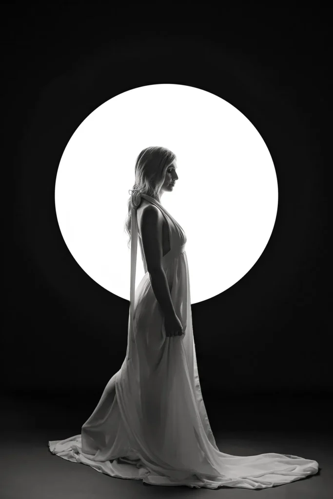 Frau im weißen Kleid tritt in einen Lichtkreis im Fotostudio