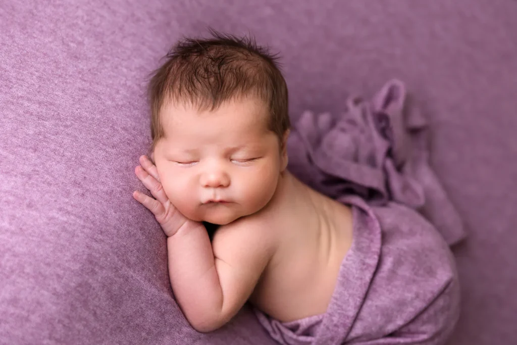 Baby auf Lila, Hand an der Wange